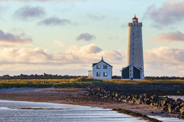a white lighthouse with a house next to it an small beach
