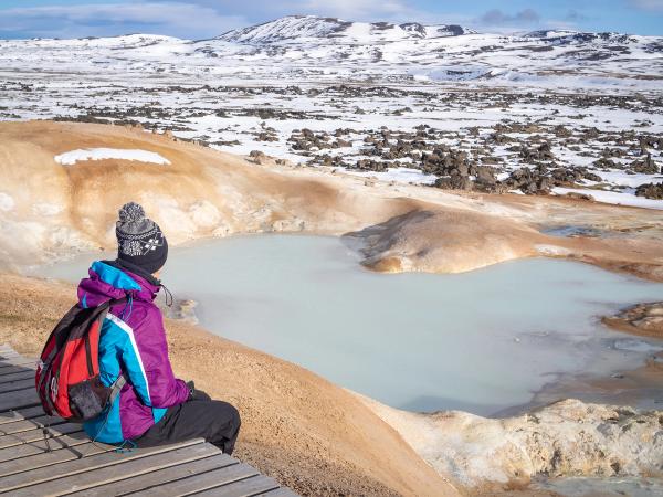 a person is sitting on a wooden platform overlooking a lake .