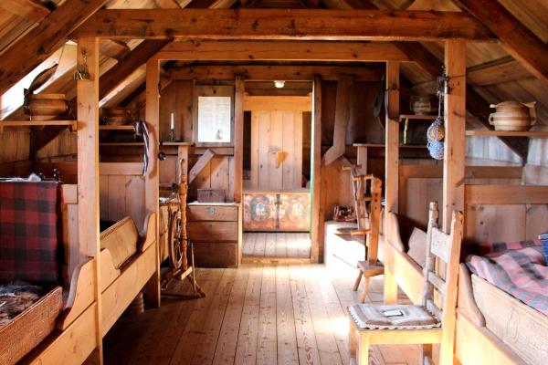 Rustic wooden attic with multiple beds, exposed beams, and traditional decor.