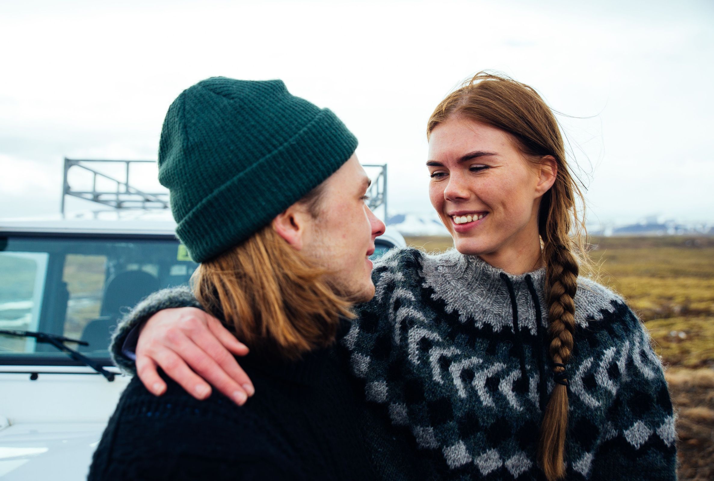 a man and a woman are standing next to each other in front of a car .