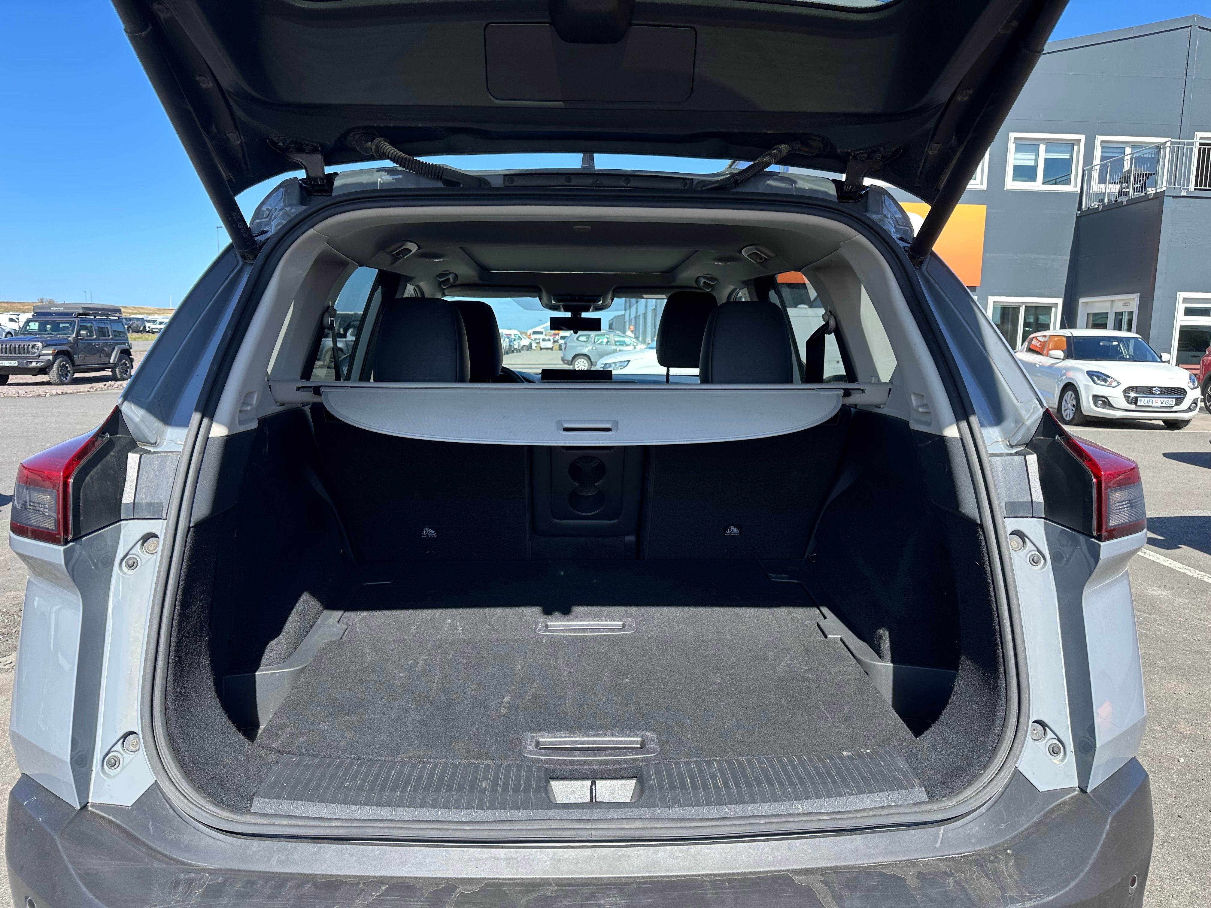 Open, empty trunk of a gray SUV with a cargo cover.