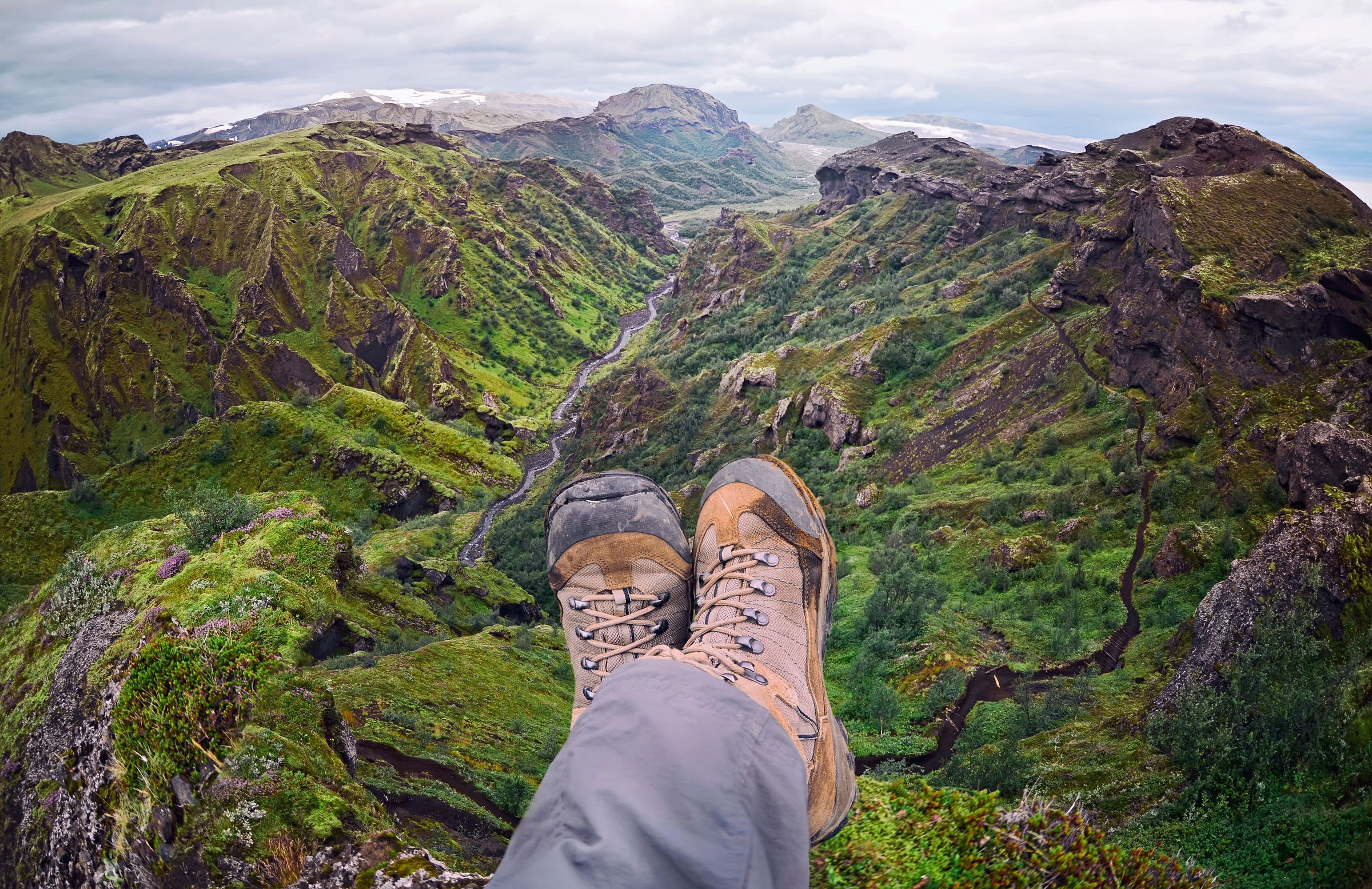 a person 's feet are resting on the edge of a mountain wearing hiking boots in iceland.