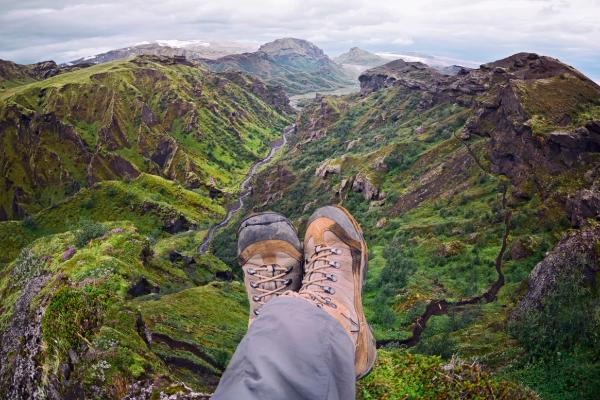 a person 's feet are resting on the edge of a mountain wearing hiking boots in iceland.