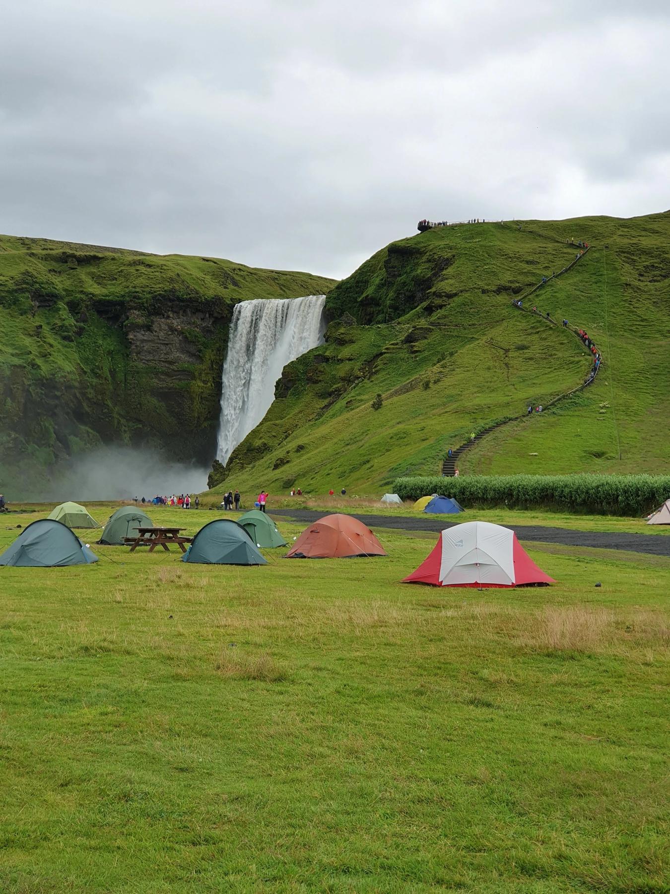 tentes dans un champ d'herbe avec une cascade en arrière-plan