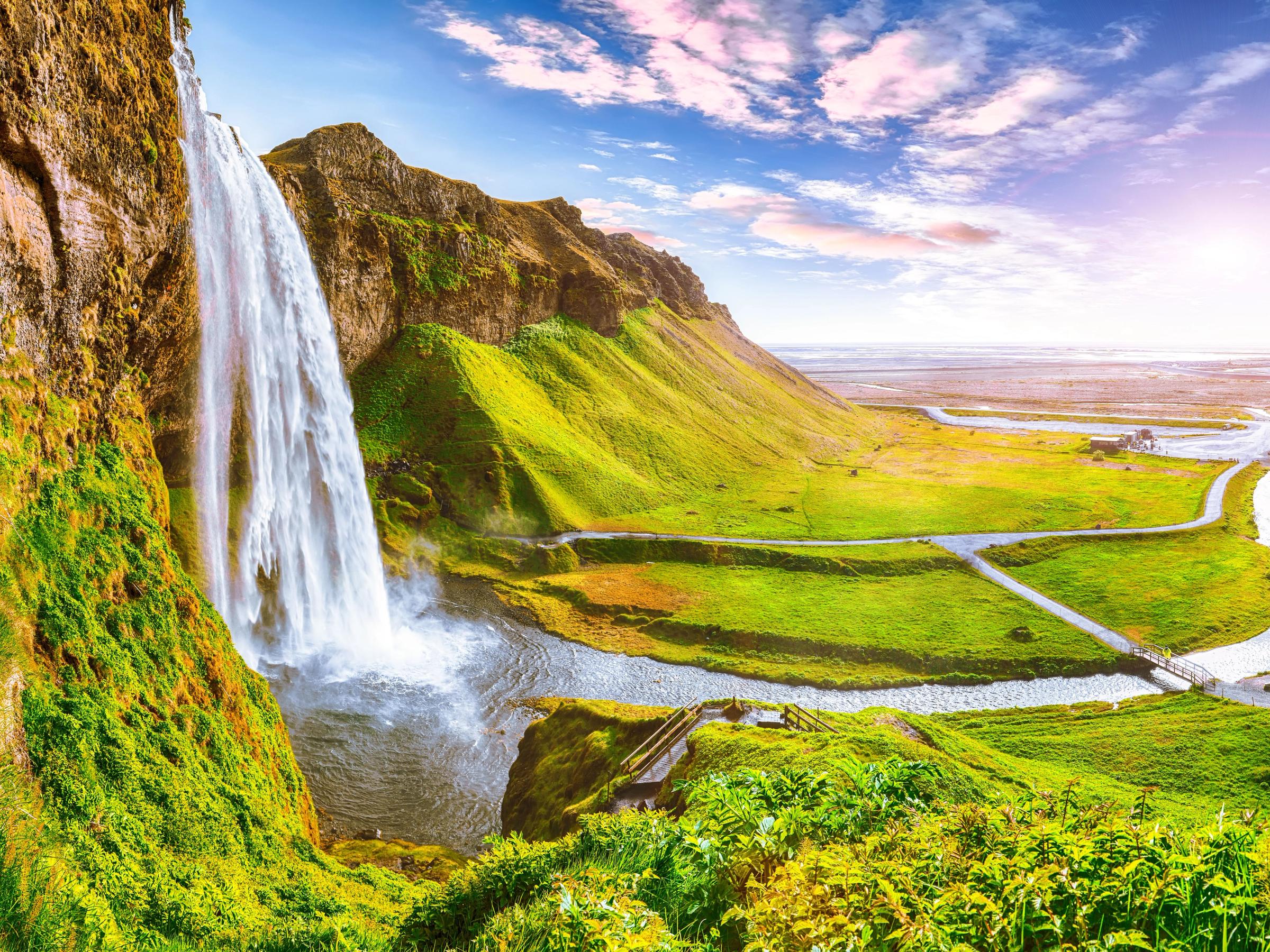 a waterfall falling into a pond on a sunny day