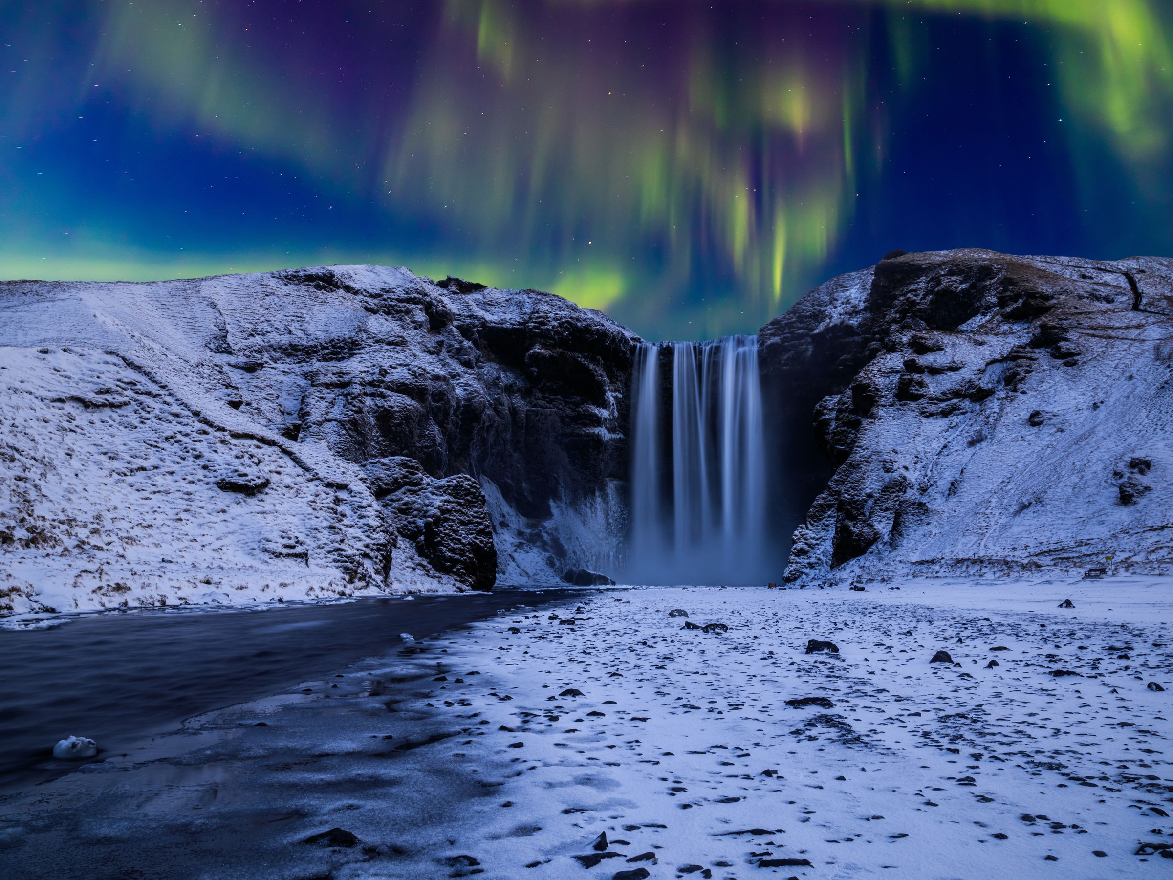 Skógafoss rodeada de nieve bajo la aurora boreal