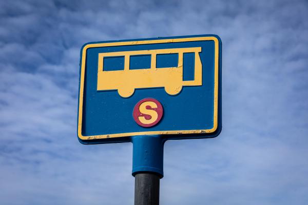 a blue and yellow bus stop sign with the letter s on it .