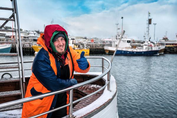 a man is leaning on the railing of a boat in the water .