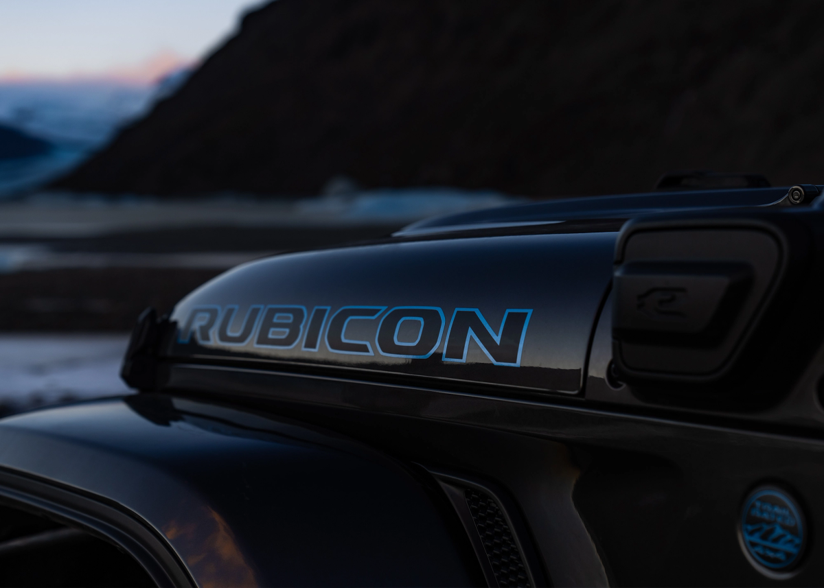 Jeep牧马人Rubicon引擎盖徽标特写，背景为海岸风光