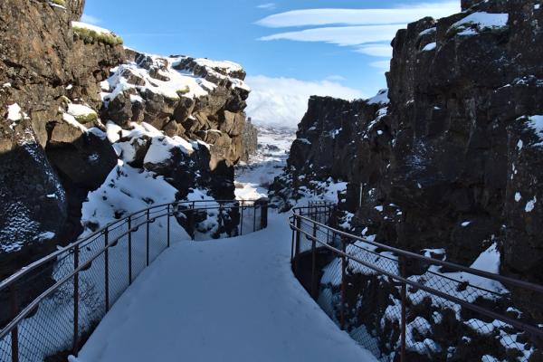 a snow covered bridge between two rocky mountains .