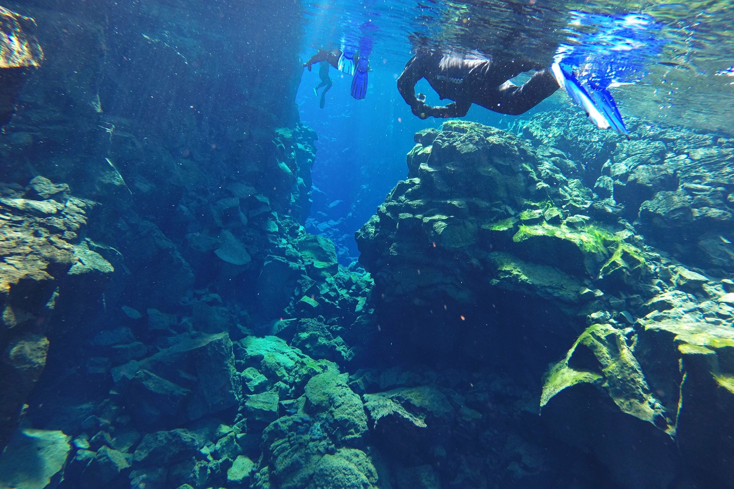 Deux personnes faisant du snorkeling entre deux plaques tectoniques