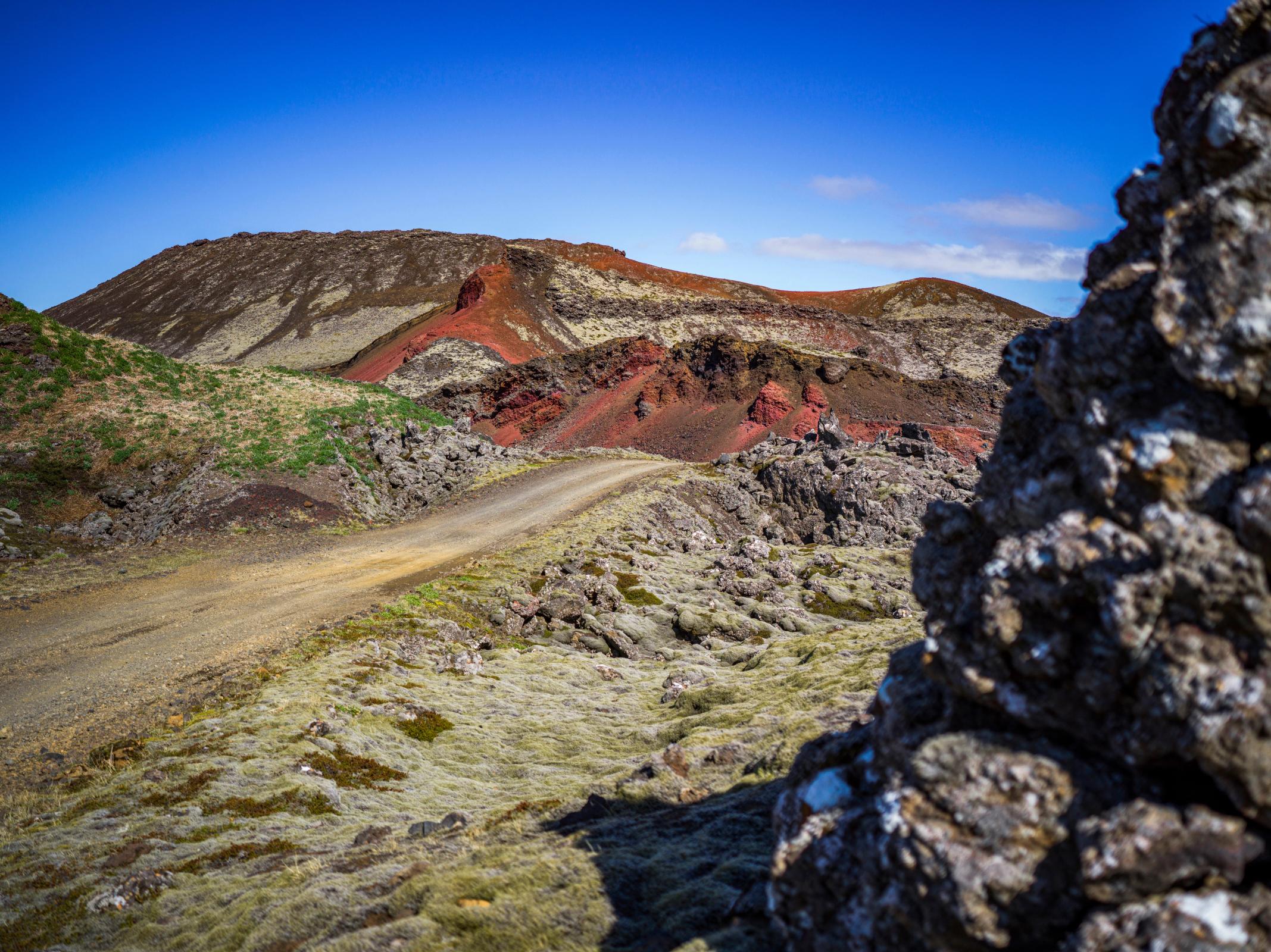 a dirt road going through a rocky area with a mountain in the background .