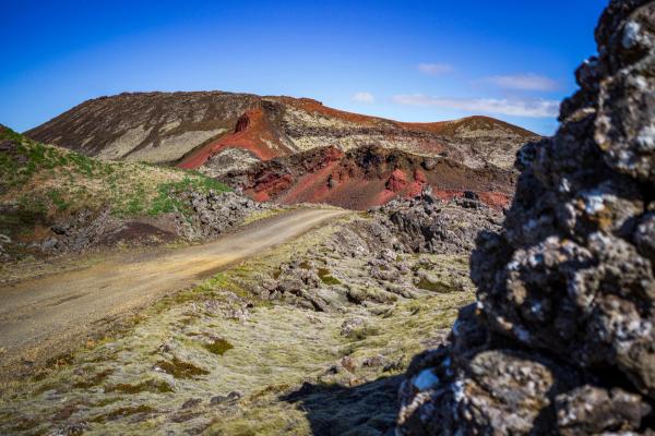 a dirt road going through a rocky area with a mountain in the background .