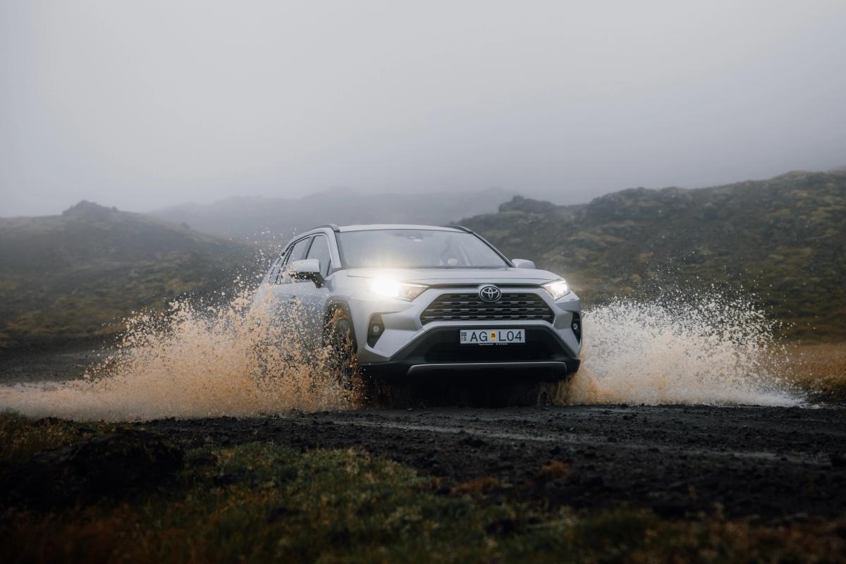 Franchissement d’un cours d’eau en RAV4 Toyota RAV4 en autotour en Islande, traversant une étendue d’eau sur une piste de gravier, avec des éclaboussures autour des roues