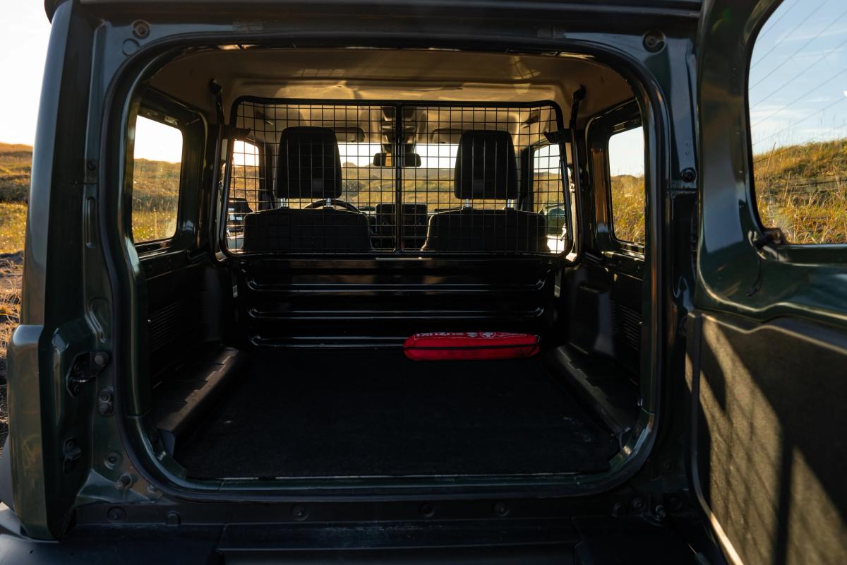 Suzuki Jimny mit Schaltgetriebe, offenem Laderaum im Heck und Trenngitter hinter den Vordersitzen