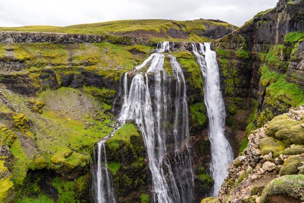 a waterfall falling from a tall green cliff