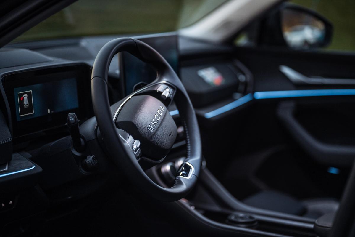Interior do Skoda Kodiaq com destaque para o volante Volante e painel de instrumentos do Skoda Kodiaq com iluminação ambiente interior azul