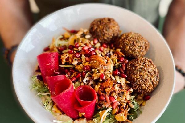 a person is holding a plate of food with falafel and vegetables .