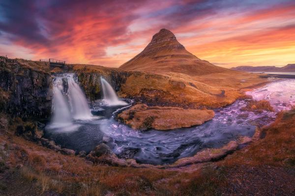 a waterfall with a mountain in the background at sunset in iceland.