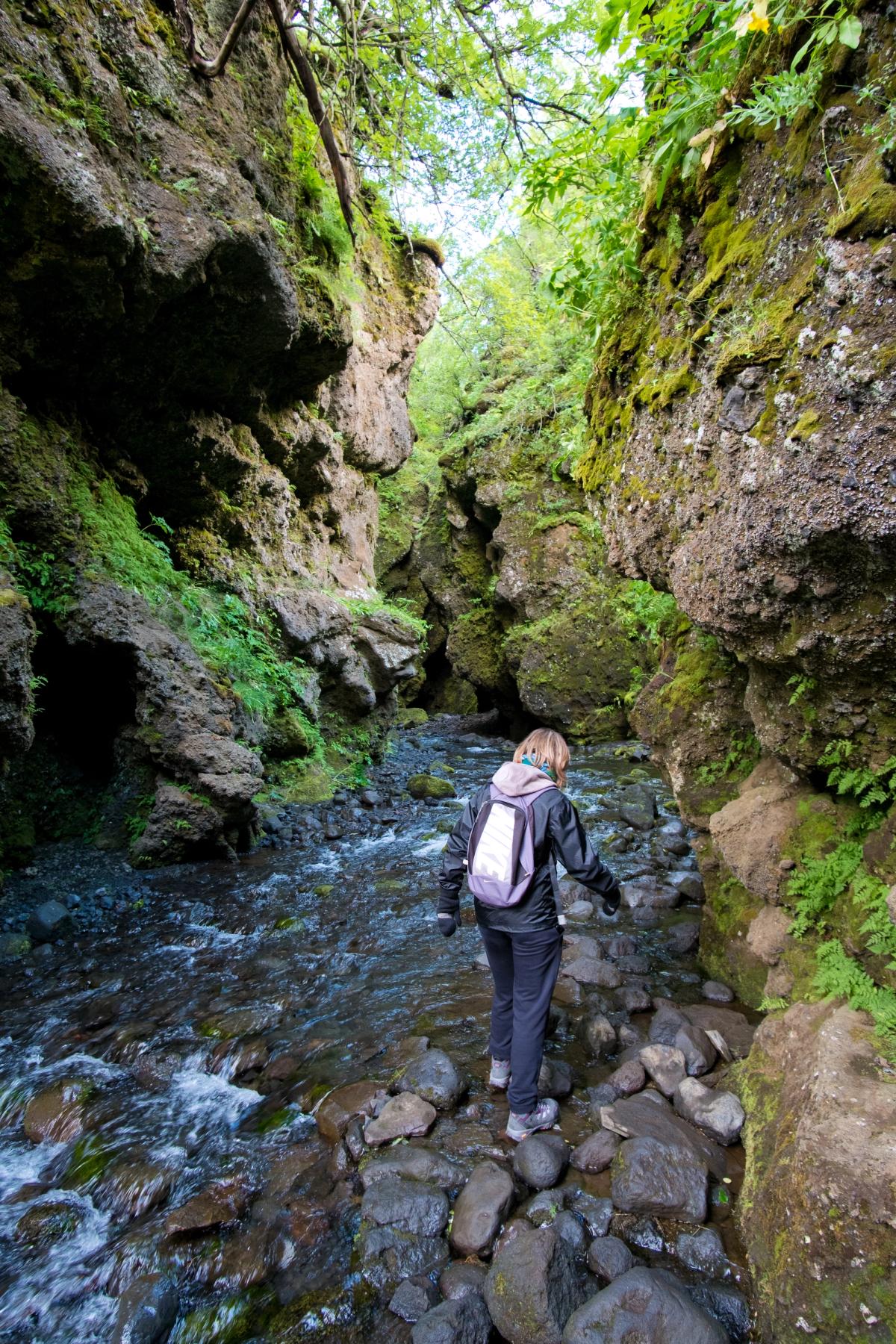 a woman with a backpack is crossing a stream