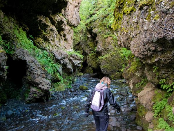 a woman with a backpack is crossing a stream