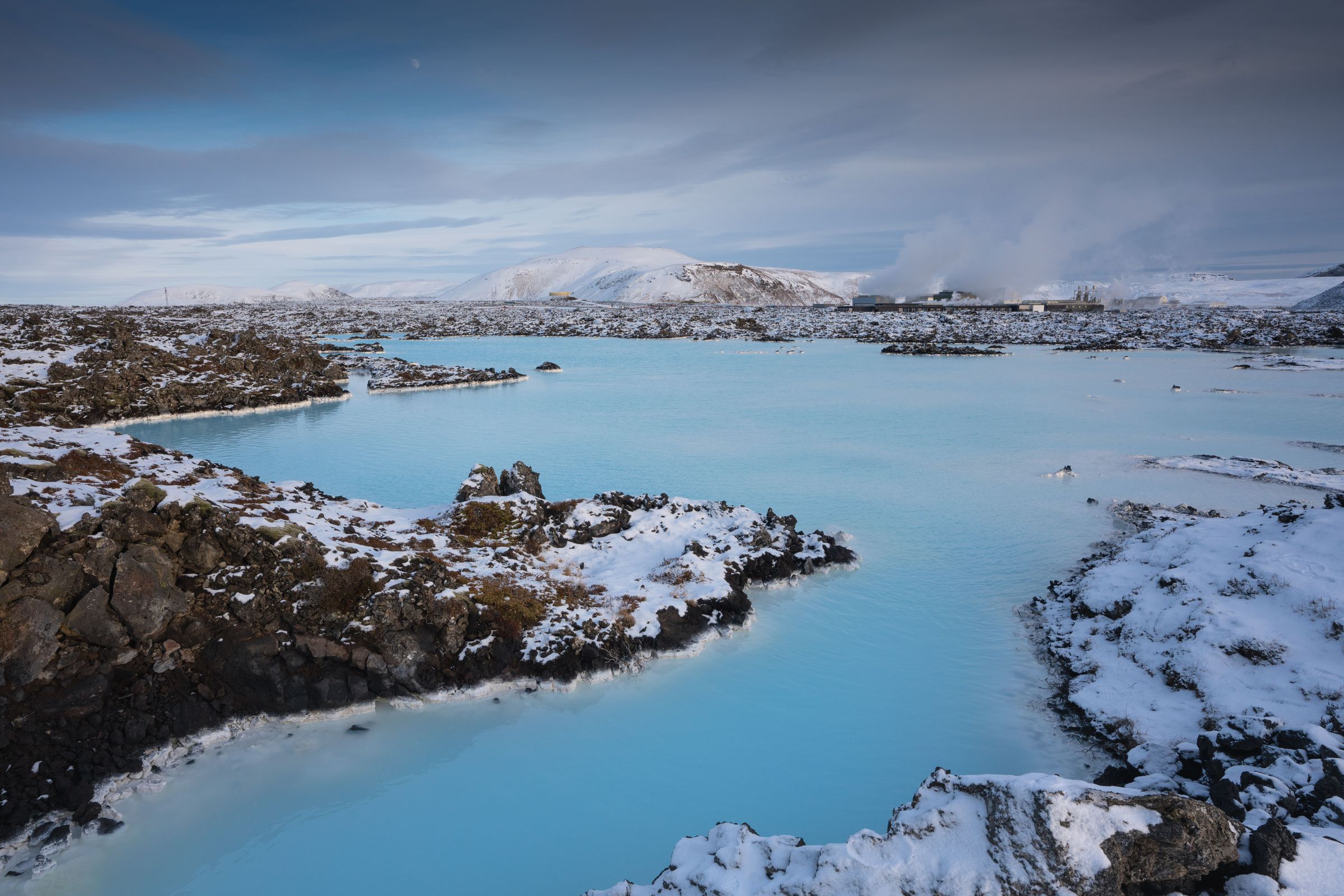 la laguna azul en Islandia está rodeada de nieve y rocas .