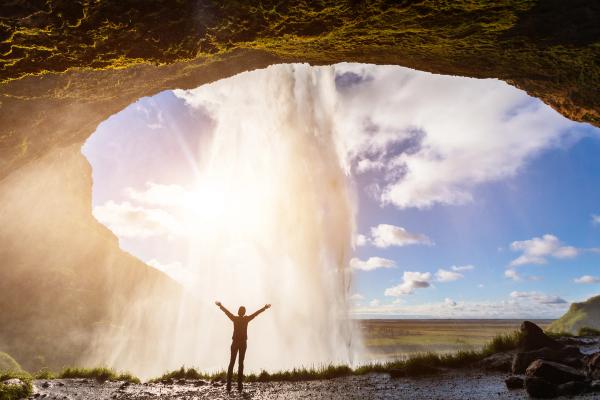 a man is standing in front of seljalandsfossl with his arms outstretched in iceland.
