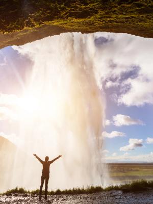 a man is standing in front of seljalandsfossl with his arms outstretched in iceland.