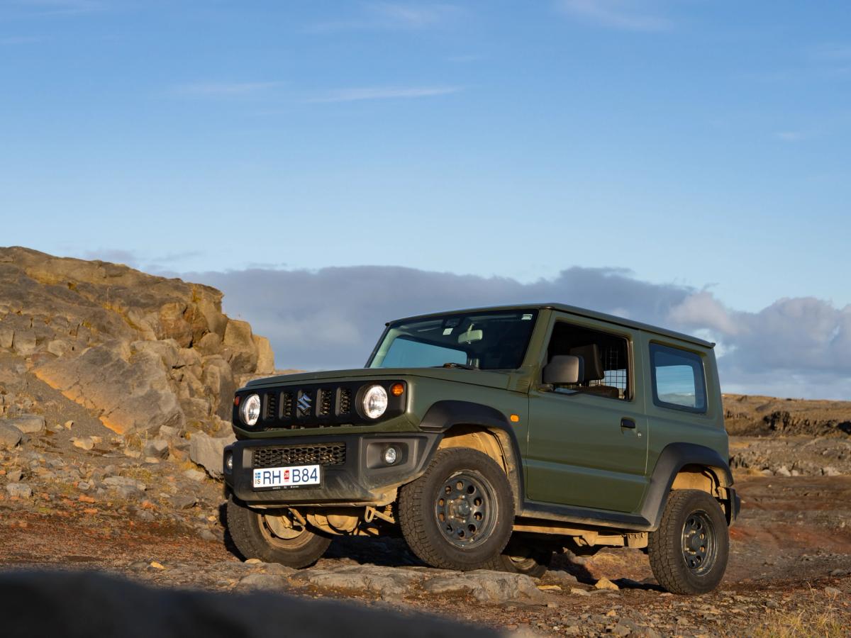 Jimny Rocky Terrain Suzuki Jimny mit Schaltgetriebe in schräger Frontansicht, auf felsigem Untergrund neben einem Felsvorsprung geparkt