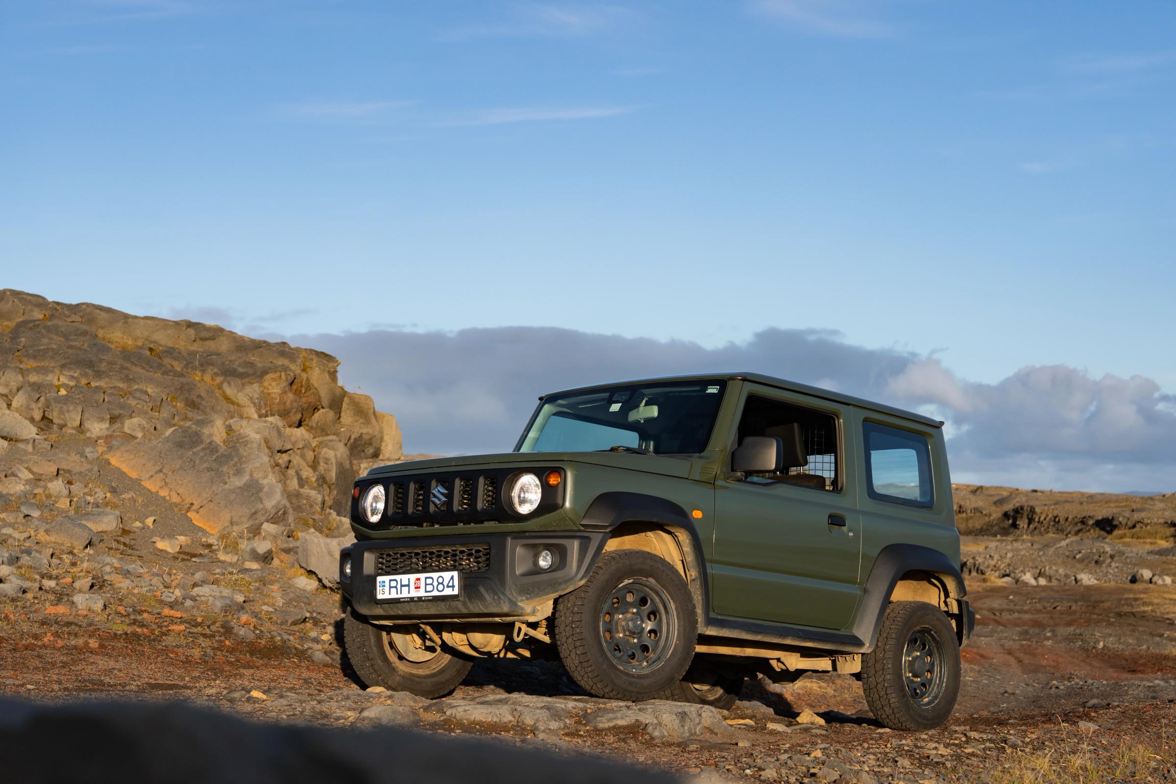 Jimny Rocky Terrain Suzuki Jimny mit Schaltgetriebe in schräger Frontansicht, auf felsigem Untergrund neben einem Felsvorsprung geparkt