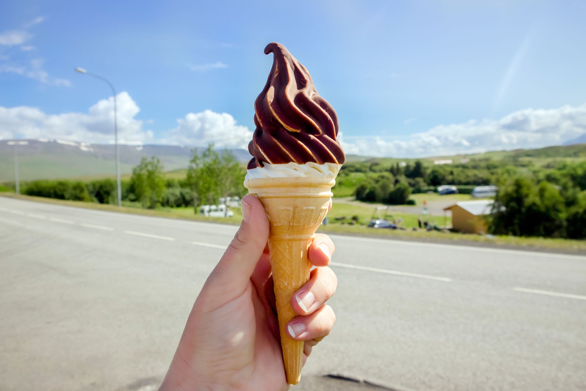 a person is holding an ice cream cone in their hand .