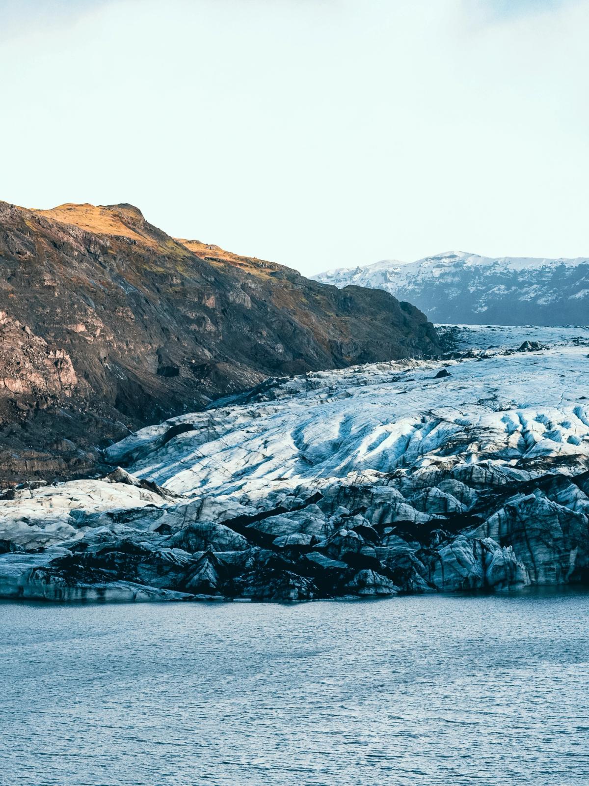 Panoramic view of a glacial lake with a large glacier and surrounding mountains.