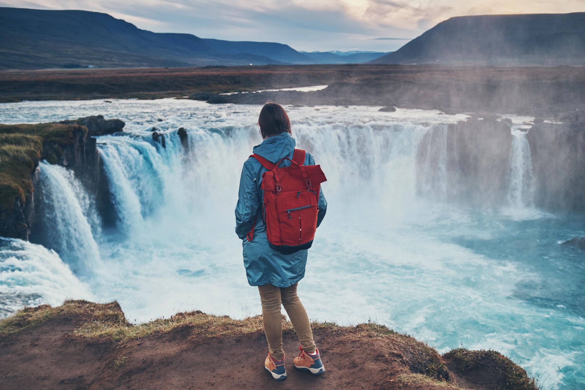 Mujer viendo Godafoss desde una roca