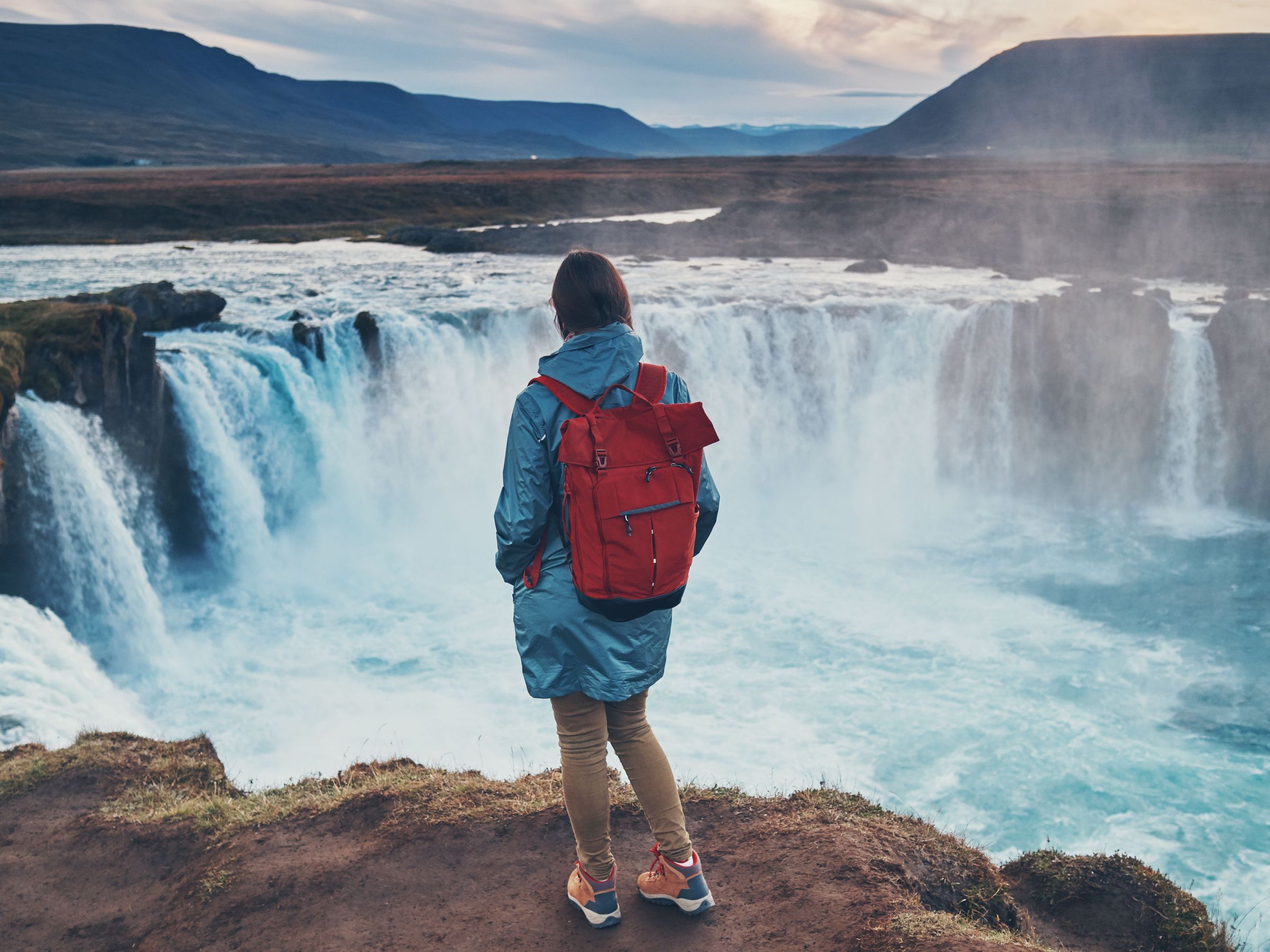 Mujer viendo Godafoss desde una roca