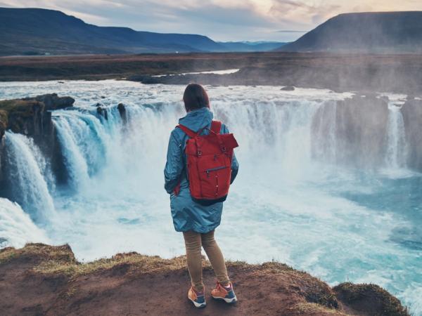 Mujer viendo Godafoss desde una roca
