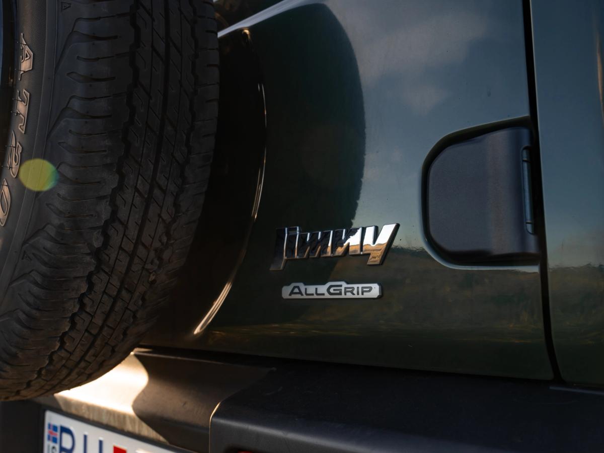 Jimny-Heckemblem Nahaufnahme des Hecks eines Suzuki Jimny mit Schaltgetriebe, Modellschriftzug, AllGrip-Emblem und Reserverad