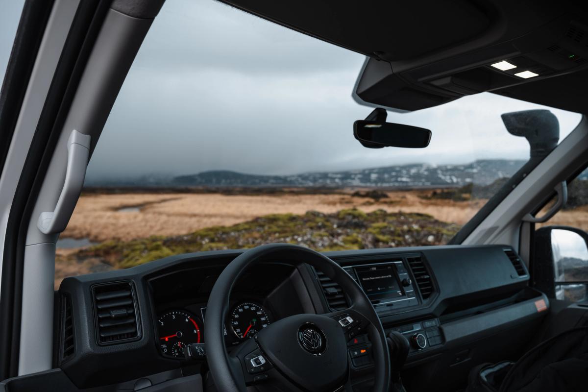 Cabina del conductor con volante y consola superior, con vistas a un páramo abierto