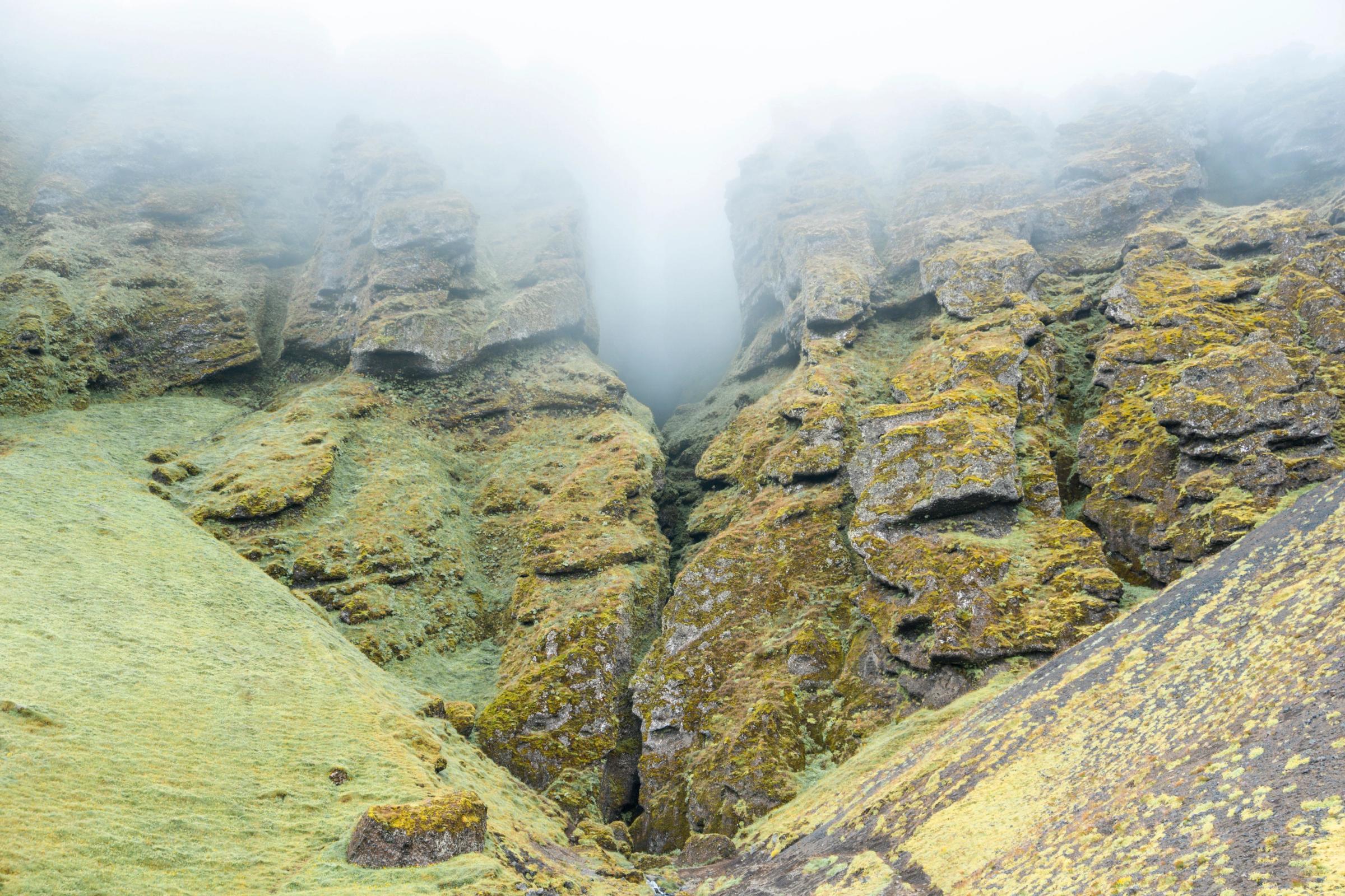 paisaje de una montaña con un cañon en medio y niebla en la parte de arriba