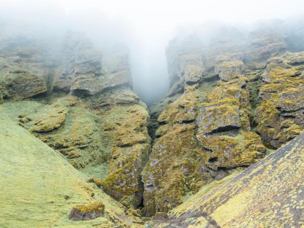 paisaje de una montaña con un cañon en medio y niebla en la parte de arriba