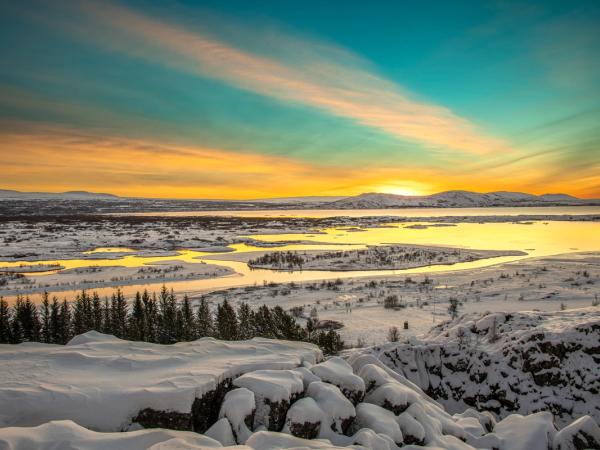 paisaje nevado con abetos y un lago al atardecer