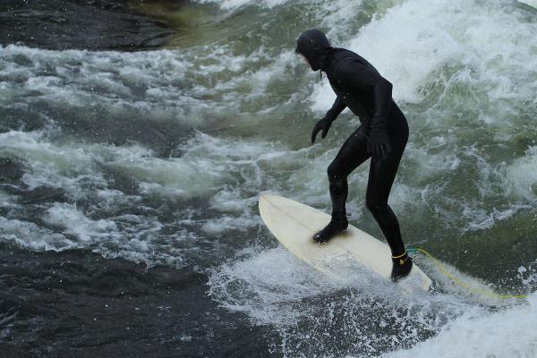 Surfing in Iceland Man in black wetsuit is surfing in waves