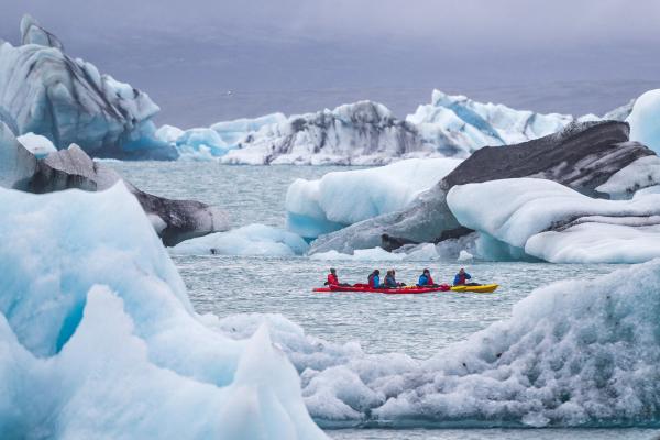 a group of people are riding kayaks in a body of water surrounded by icebergs in iceland. .