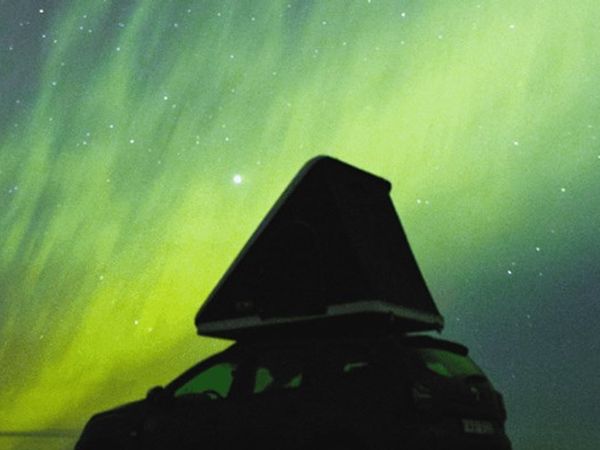 a person in a hood is looking at the aurora borealis .