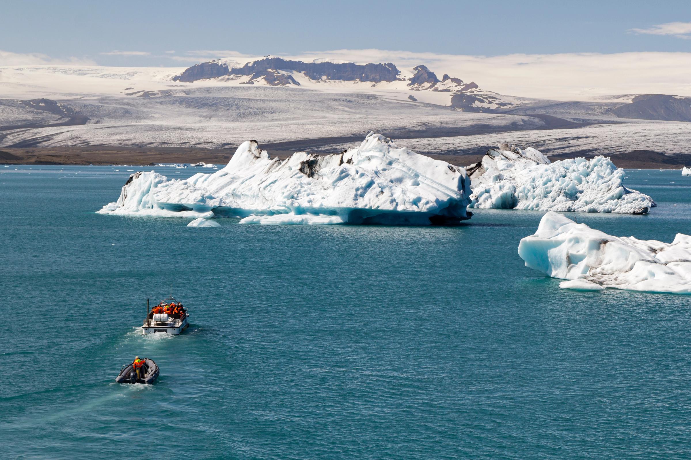 a boat is floating in the water near a large iceberg .