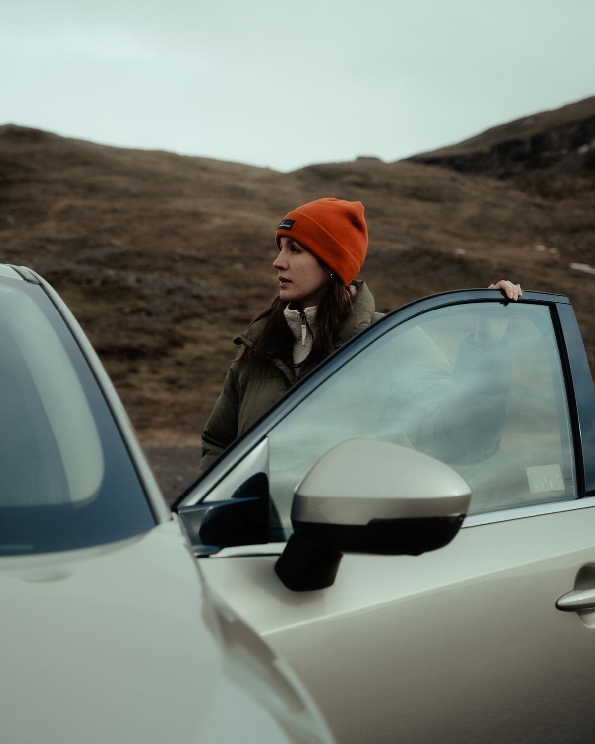 a woman in an orange hat is standing next to a car