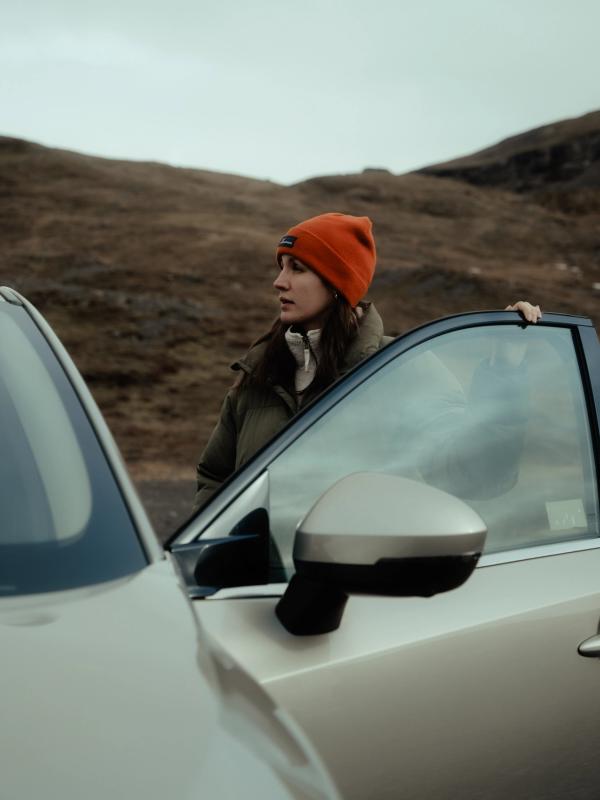 a woman in an orange hat is standing next to a car