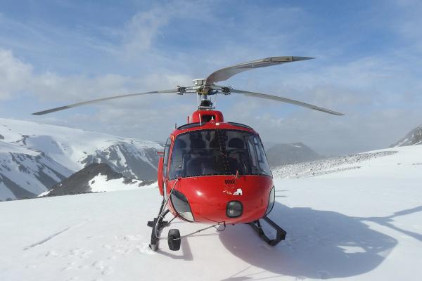 a red helicopter is sitting on top of a glacier, Iceland
