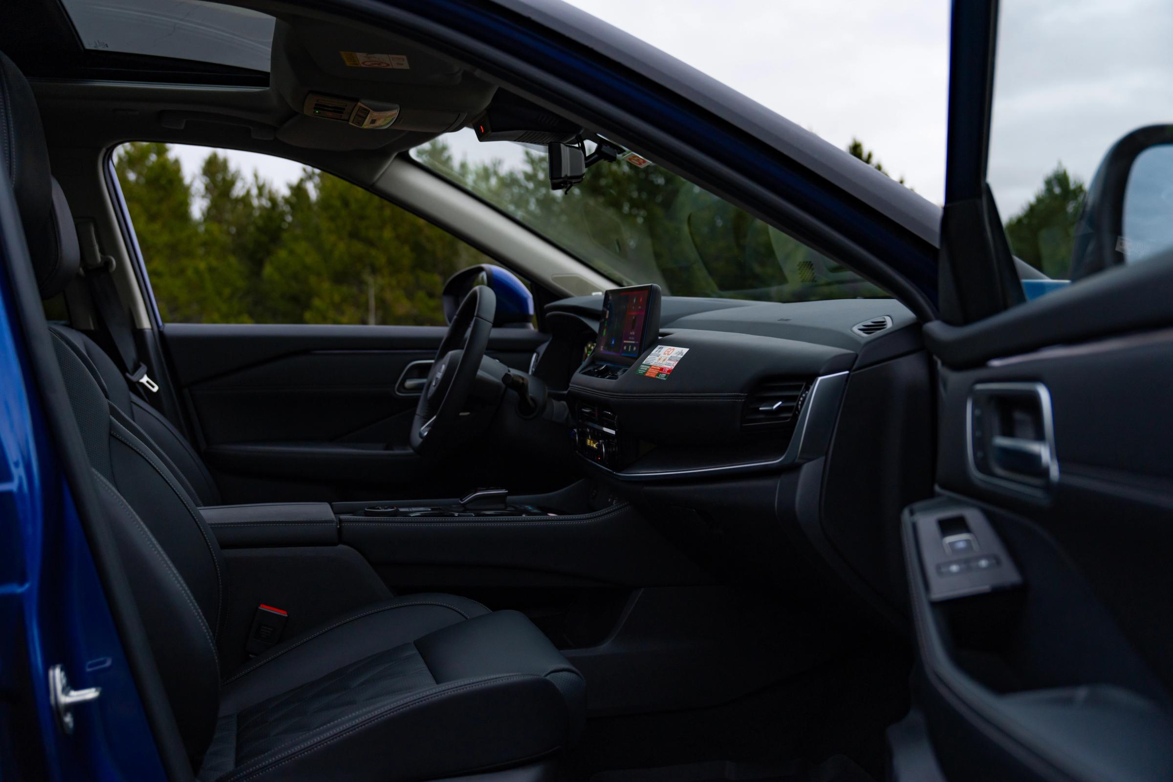 Vista del interior de un Nissan X-Trail, con los asientos delanteros y el salpicadero vistos a través de la puerta abierta