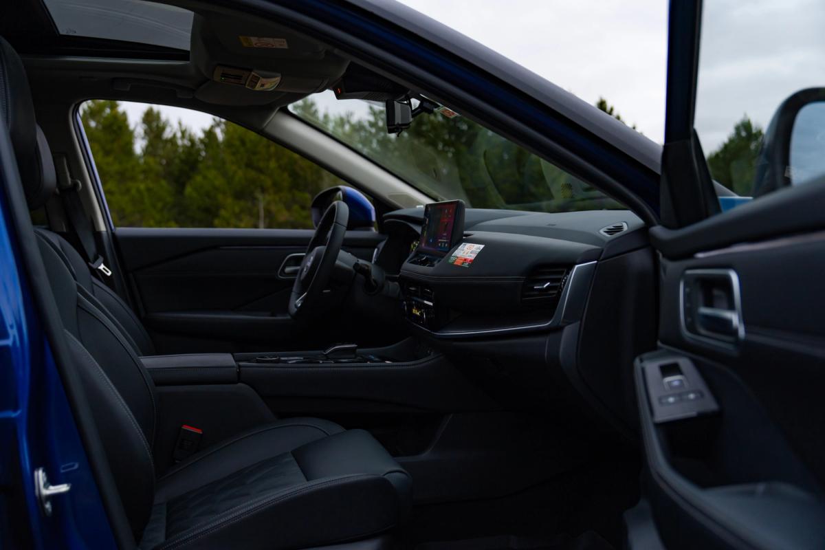 Vista del interior de un Nissan X-Trail, con los asientos delanteros y el salpicadero vistos a través de la puerta abierta