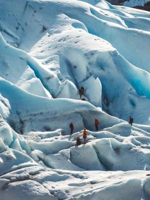 a group of people are standing on top of a large iceberg .